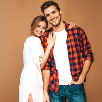 Portrait of Smiling Beautiful Girl and her Handsome Boyfriend laughing.Happy Cheerful Family.Valentine's Day. Posing on beige wall. Hugging